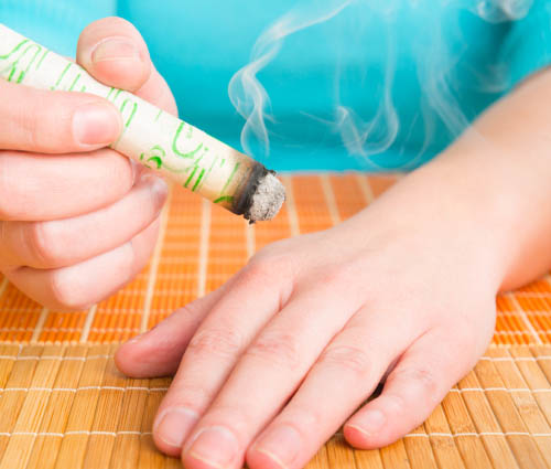 Main tenant un baton de moxibustion fumant